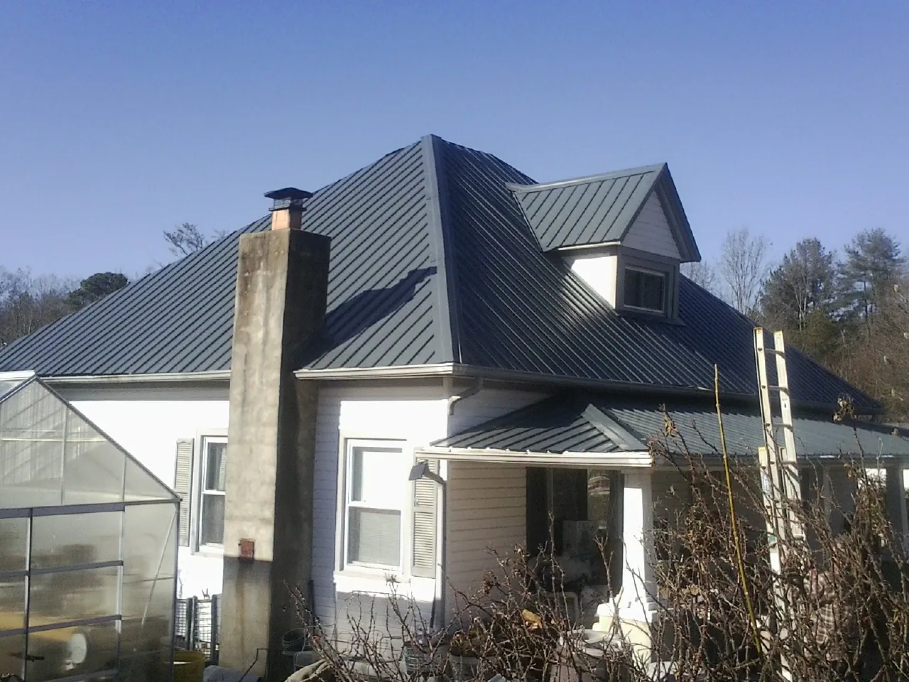 Dark blue standing seam metal roof on a white farmhouse with dormer — Slate & Tile Roof Repair by Roofing Brothers in West Richland