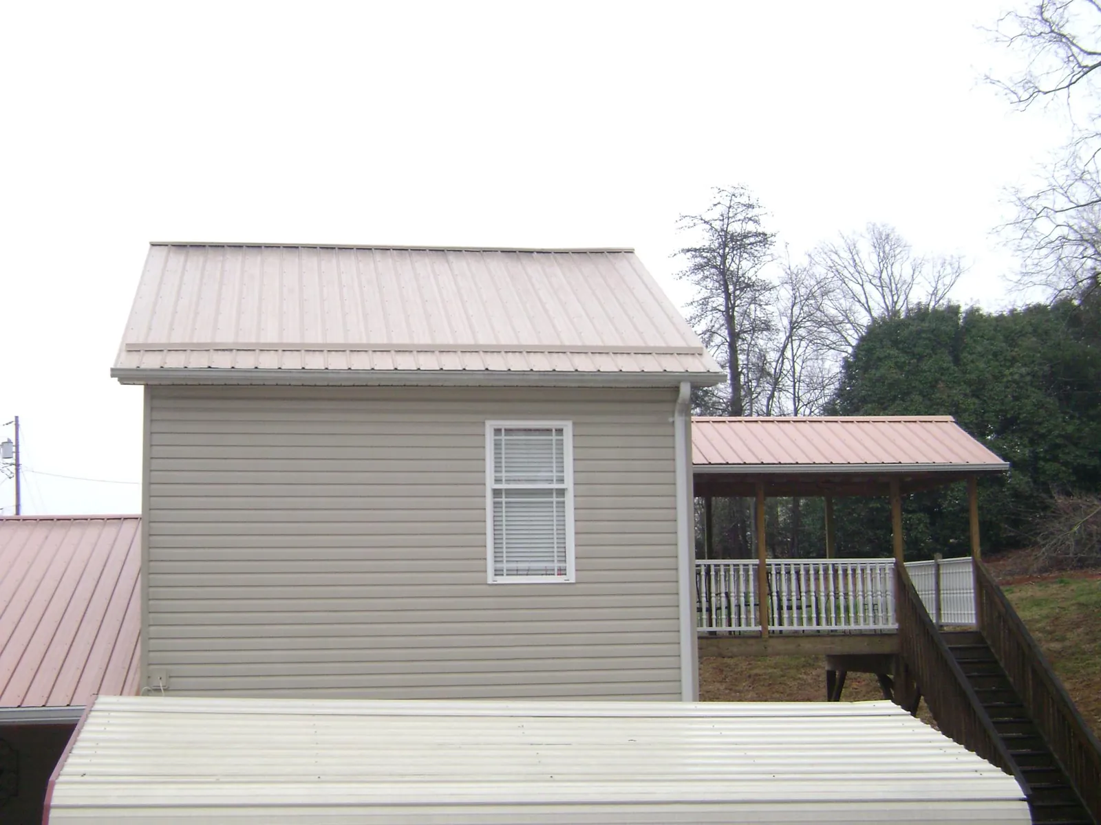 Tan metal roofs on a two story addition and attached porch, from a Roof Replacement job in West Richland