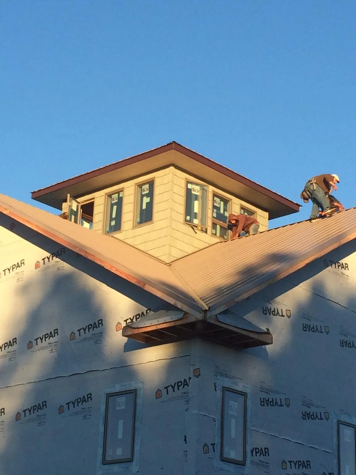 Roofers working around a rooftop cupola on a new metal roof at sunset — Roof Waterproofing in West Richland by Roofing Brothers